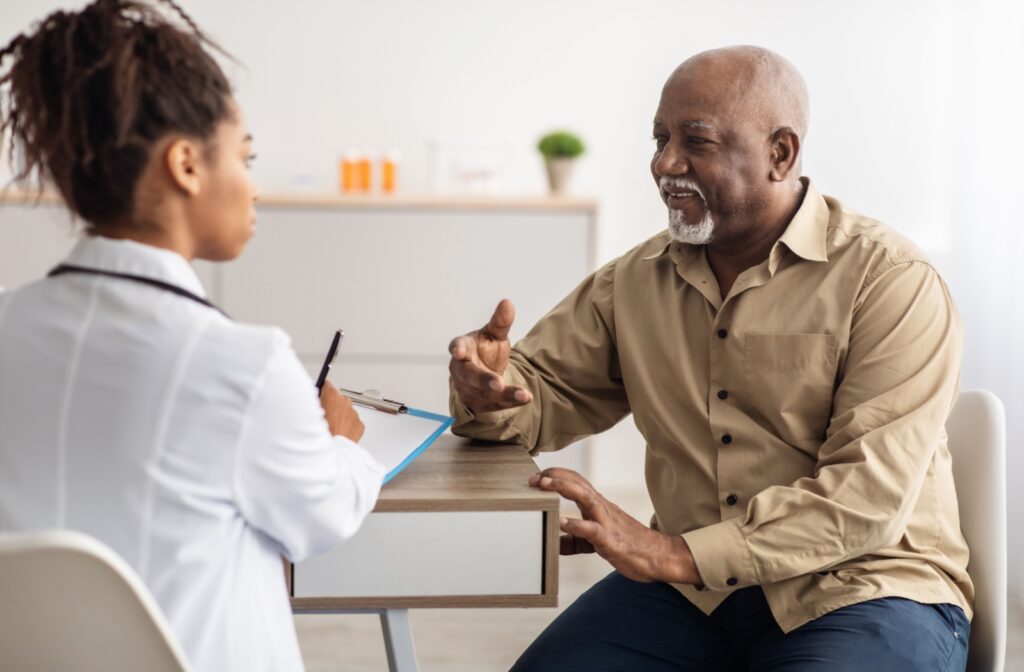 An older man and a female nurse sitting at a table together and having a conversation.