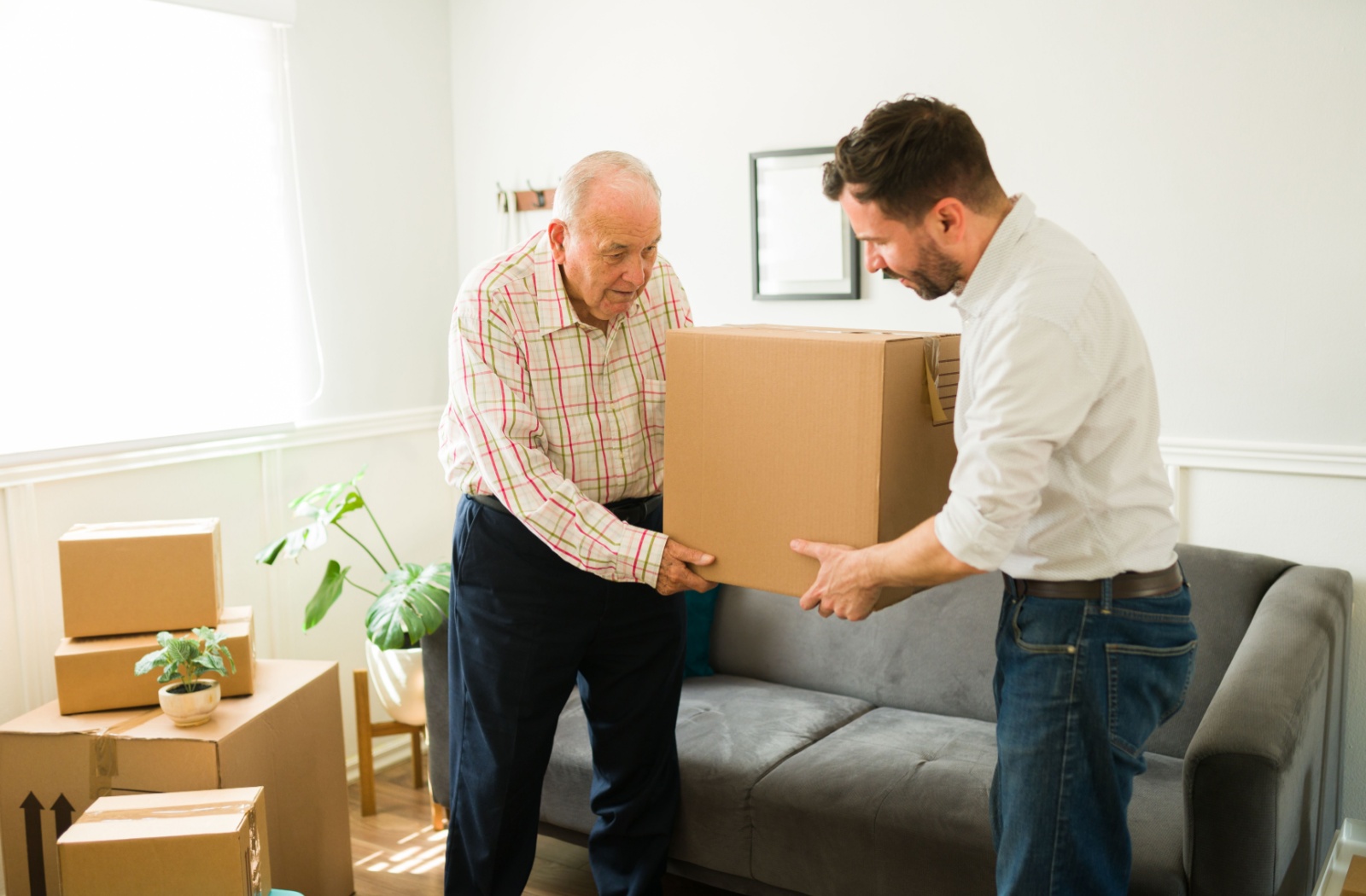 An older man handing a moving box to a younger man.