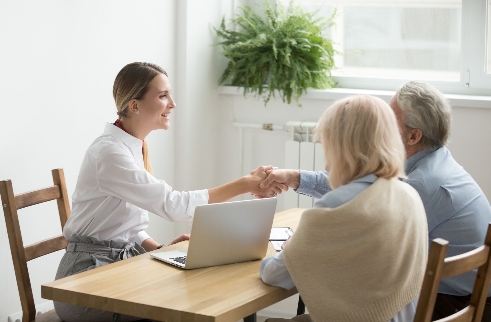 An older couple and a female attorney sitting at a table formalizing a power of attorney agreement.