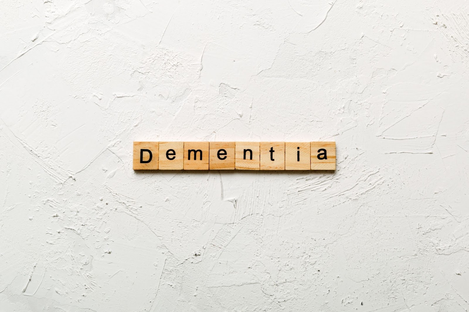 Scrabble letter tiles that spell 'dementia' are on a white background.