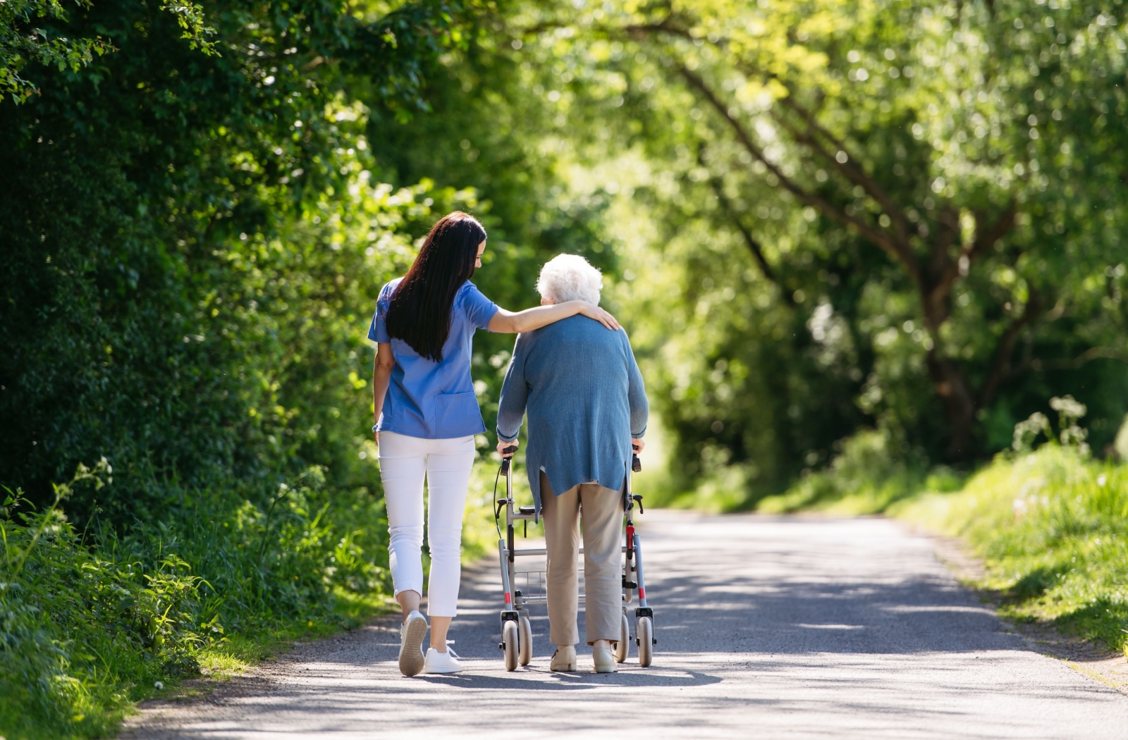 A senior struggling with dementia taking a walk in the park with their caregiver