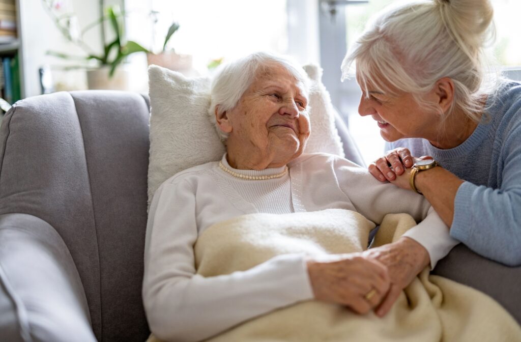 A senior with dementia relaxing on the couch and chatting with their friend