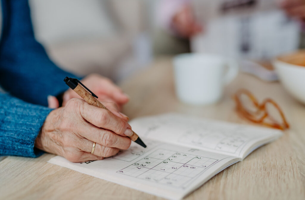 An older adult in memory care doing a Sudoku to boost their brain.