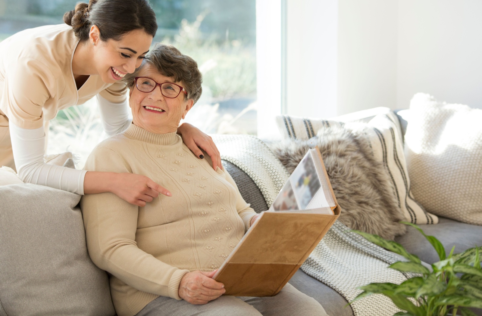 A senior with early-stage dementia in memory care shows a friendly nurse pictures from a family photo album