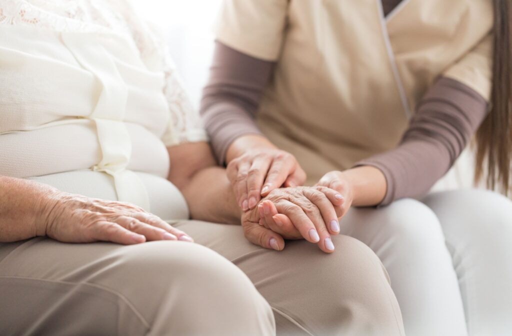 a caregiver holding hands of a senior with Parkinson's